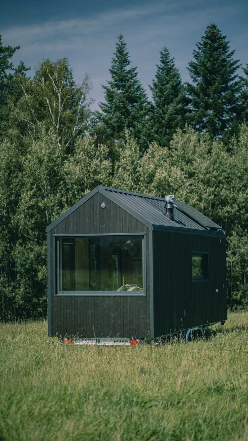 Mobiles Ferienhaus mit verglaster Giebelfront, aufgestellt am Waldrand